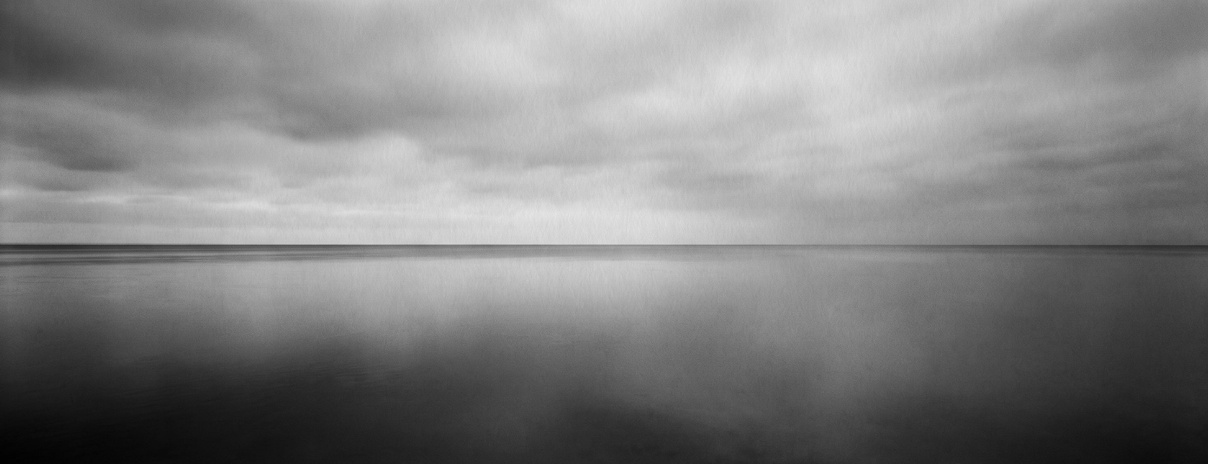 A calm sea horizon under an overcast sky.
